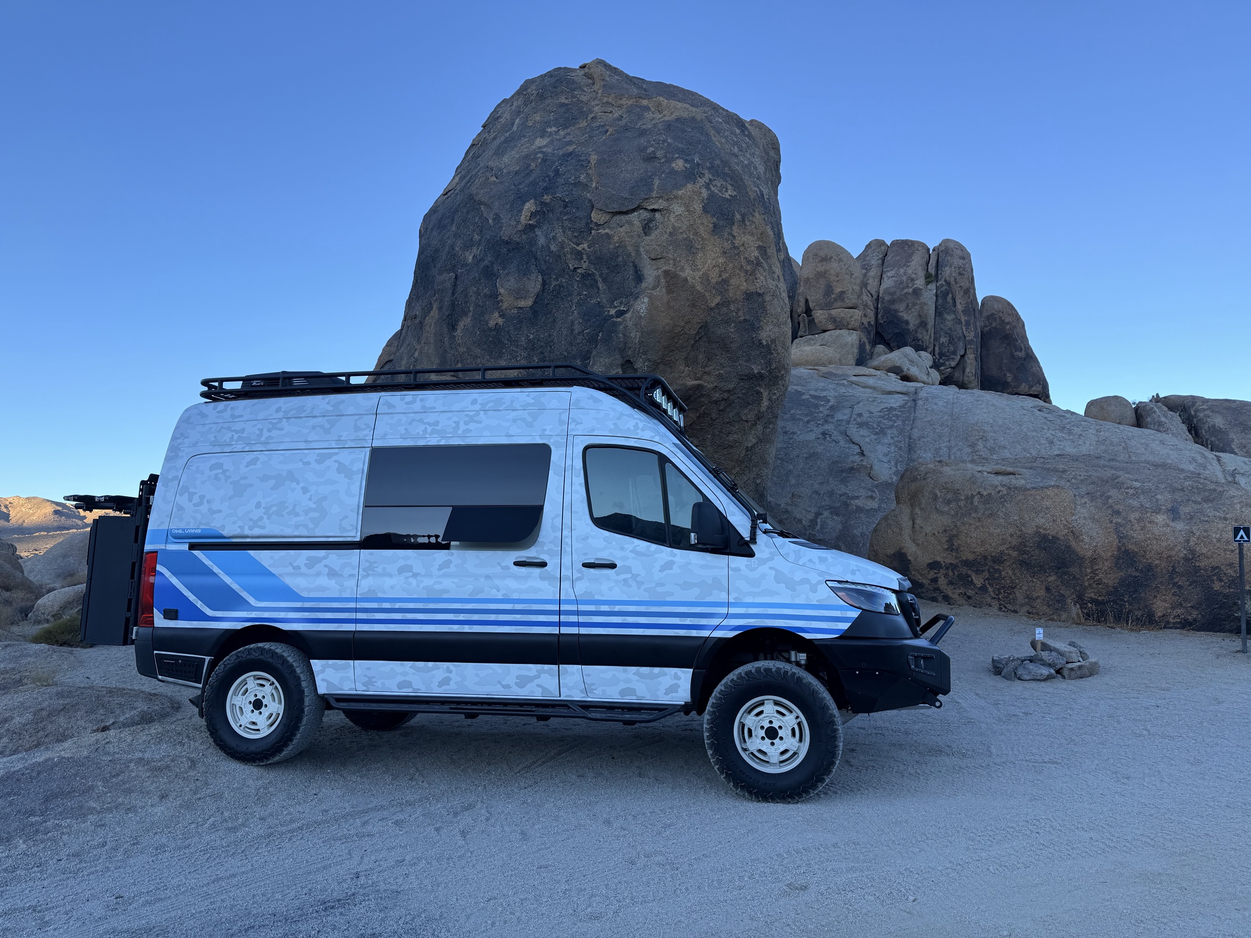 2021 Storyteller Overland Stealth Sprinter parked among desert boulders at golden hour